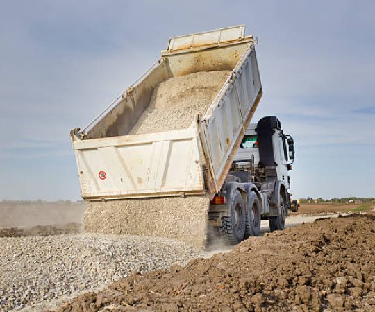 Tipping truck unloading gravel on road construction site
